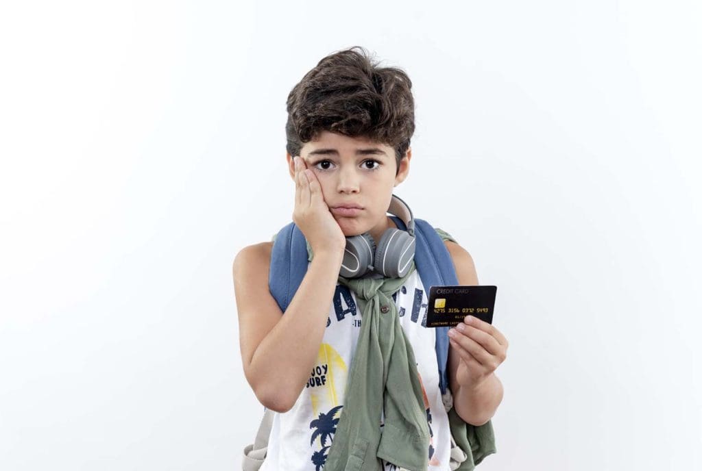 sad little schoolboy wearing back bag headphones holding headphones putting hand cheek