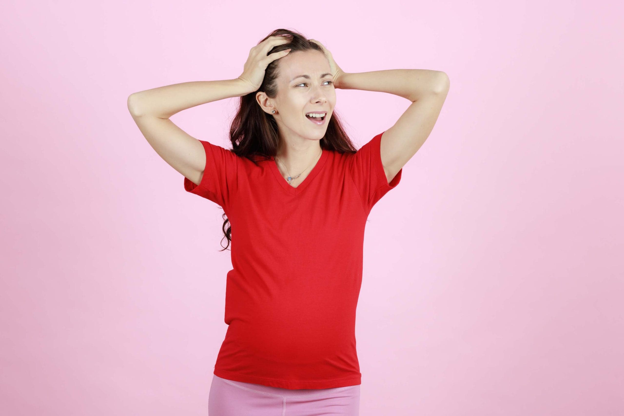 Young and beautiful pregnant woman in red t-shirt using hands ho